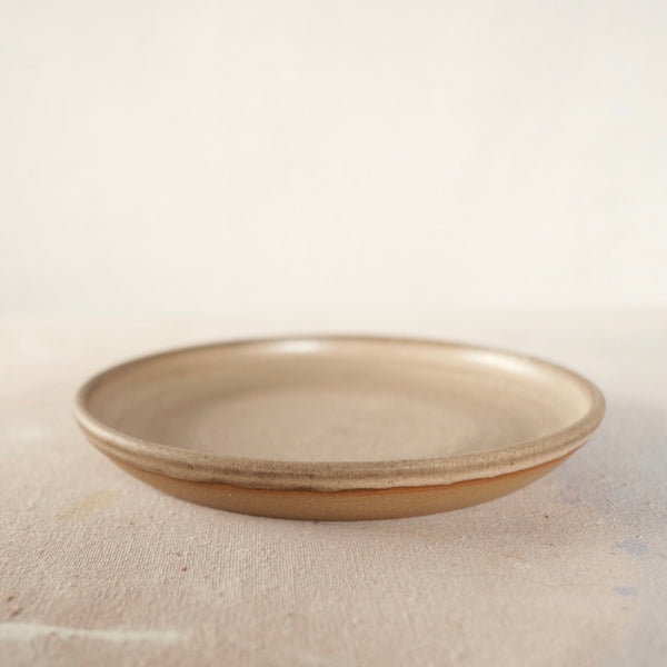 Country Rim Lunch Plate sits upright at a low angle, showing its glazed shallow interior and exposed clay base.